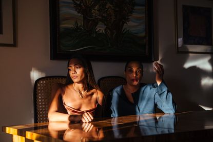 Photo of 2 women siting at a table in cane chairs