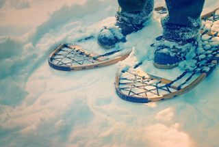 A man wears old-fashioned wooden snowshoes in the snow