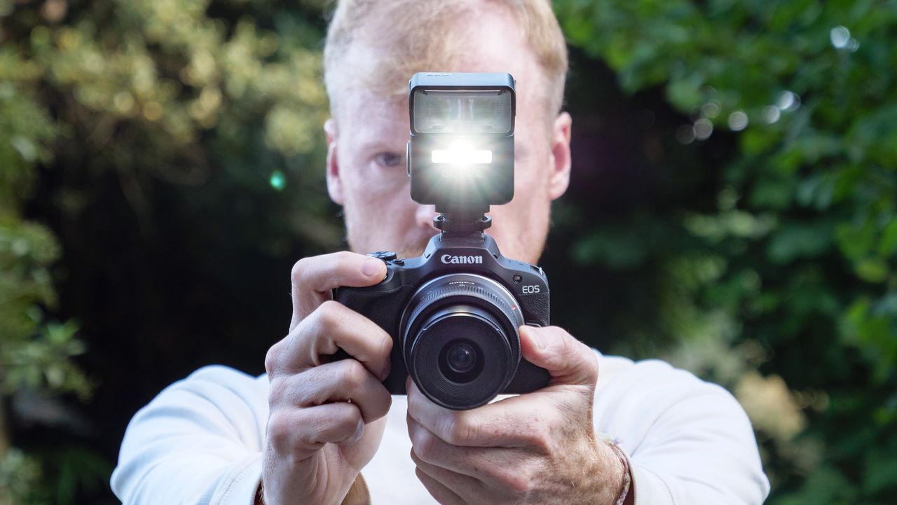 Godox iT32 camera flash attached to a Canon camera, it's model light is on, held by photographer and TechRadar's Cameras Editor Tim Coleman