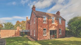 large brick property with glass side extension, bifold doors and large lawn