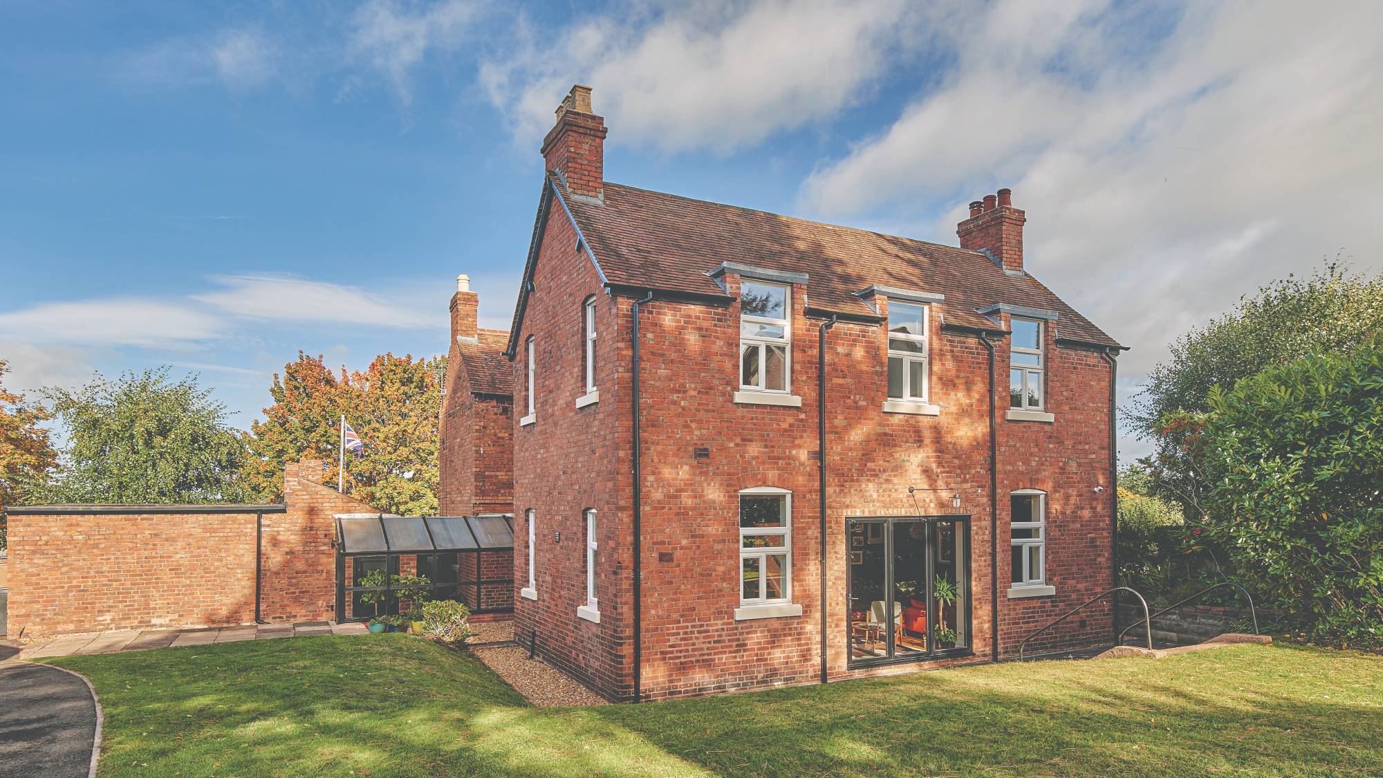 large brick property with glass side extension, bifold doors and large lawn