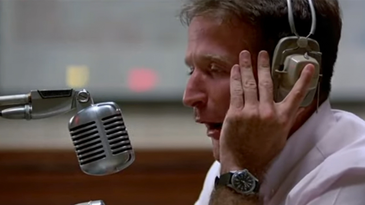 Robin Williams with headphones oon, talking into a microphone in Good Morning Vietnam