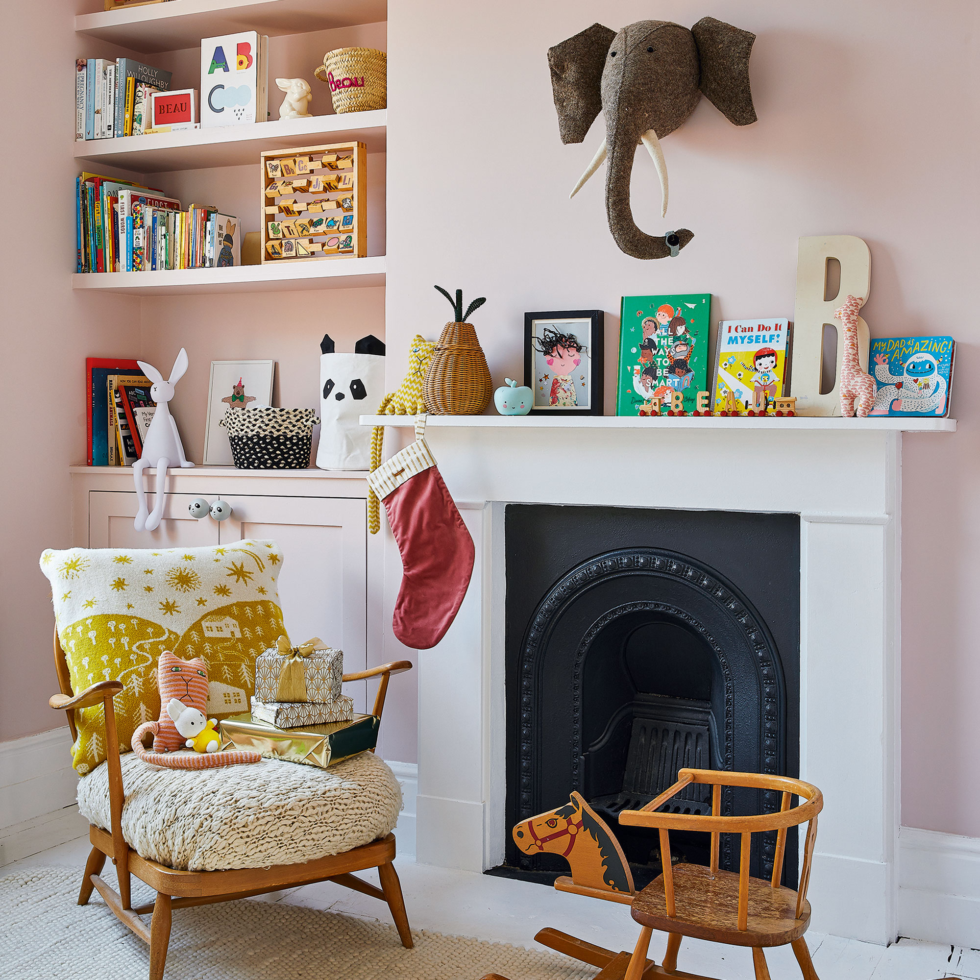Soft pink painted children's room with white fireplace, and elephant head on wall above