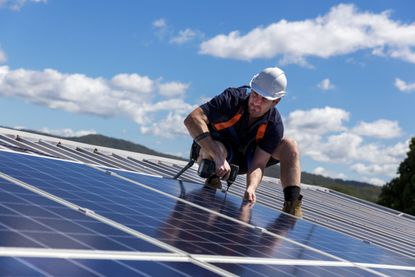 Worker installing rooftop solar panels.