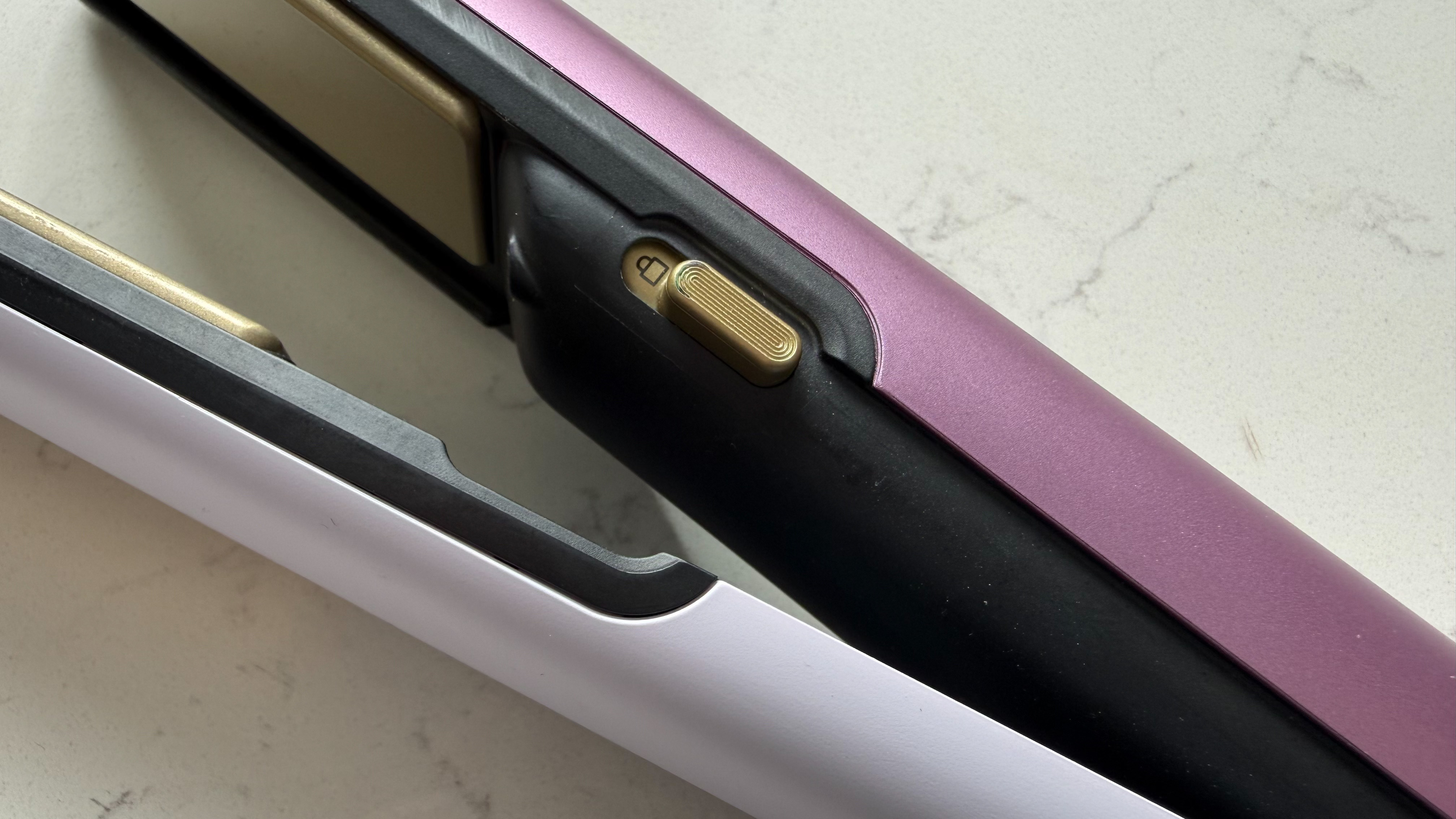 Close-up of the gold lock switch on the Shark SilkiPro Straight showing the two-tone purple and lilac design of the arms