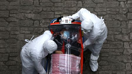 A South Korean patient is transported by medical staff on a Covid secure stretcher.