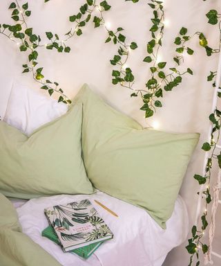 A bedroom with ivy string fairy lights and light green pillowcase decor