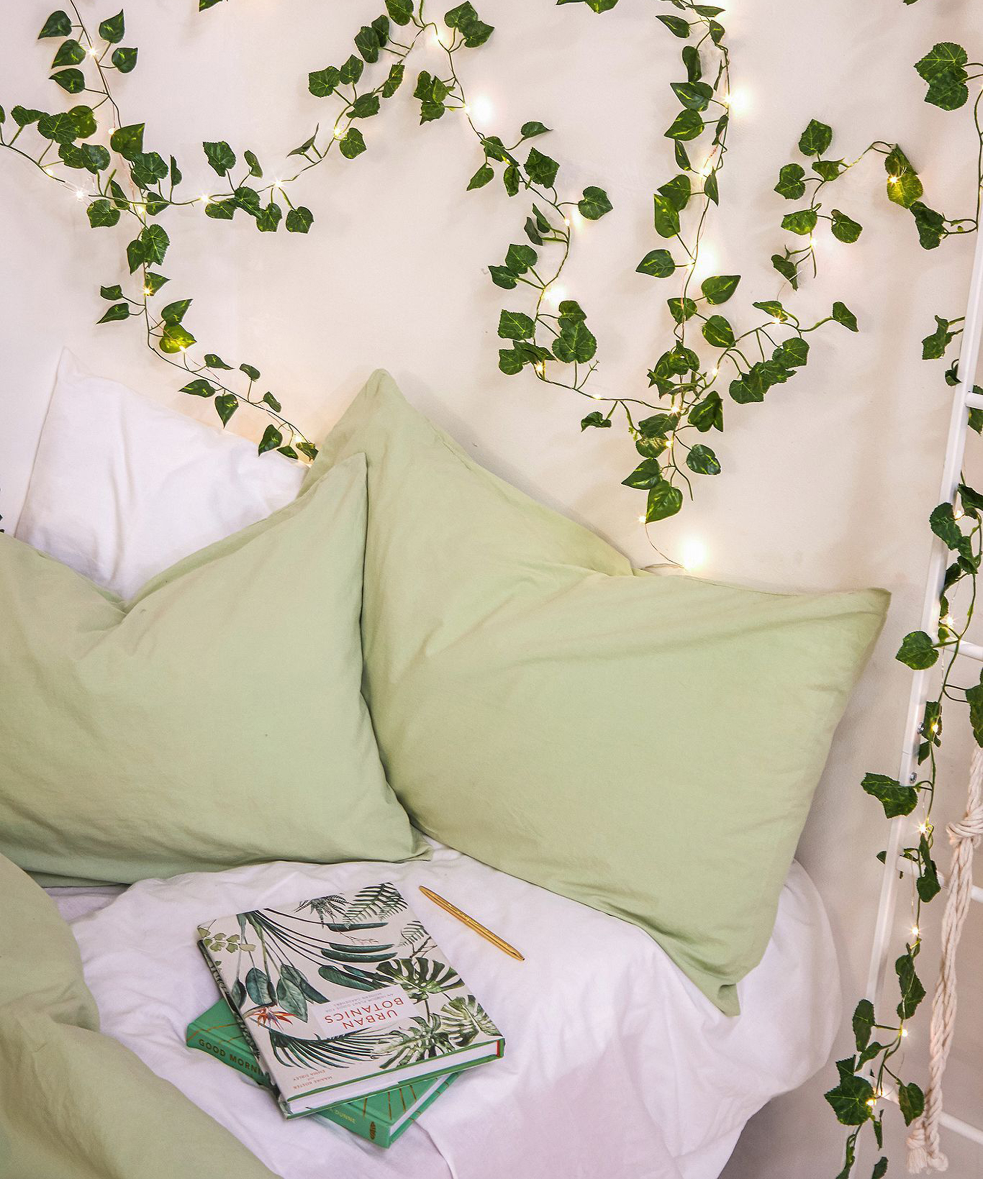 A bedroom with ivy string fairy lights and light green pillowcase decor