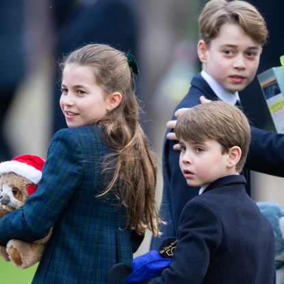 Princess Charlotte, Prince Louis, and Prince George look surprised while holding Christmas gifts, as their mom Kate Middleton looks happy