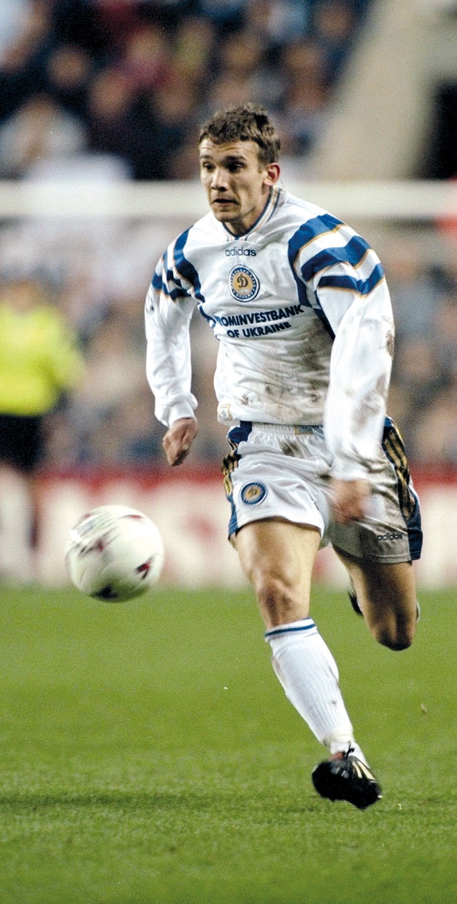 A football player in a white and blue jersey sprinting on the field, capturing the intensity of training sessions described in the article about the challenges faced by athletes.