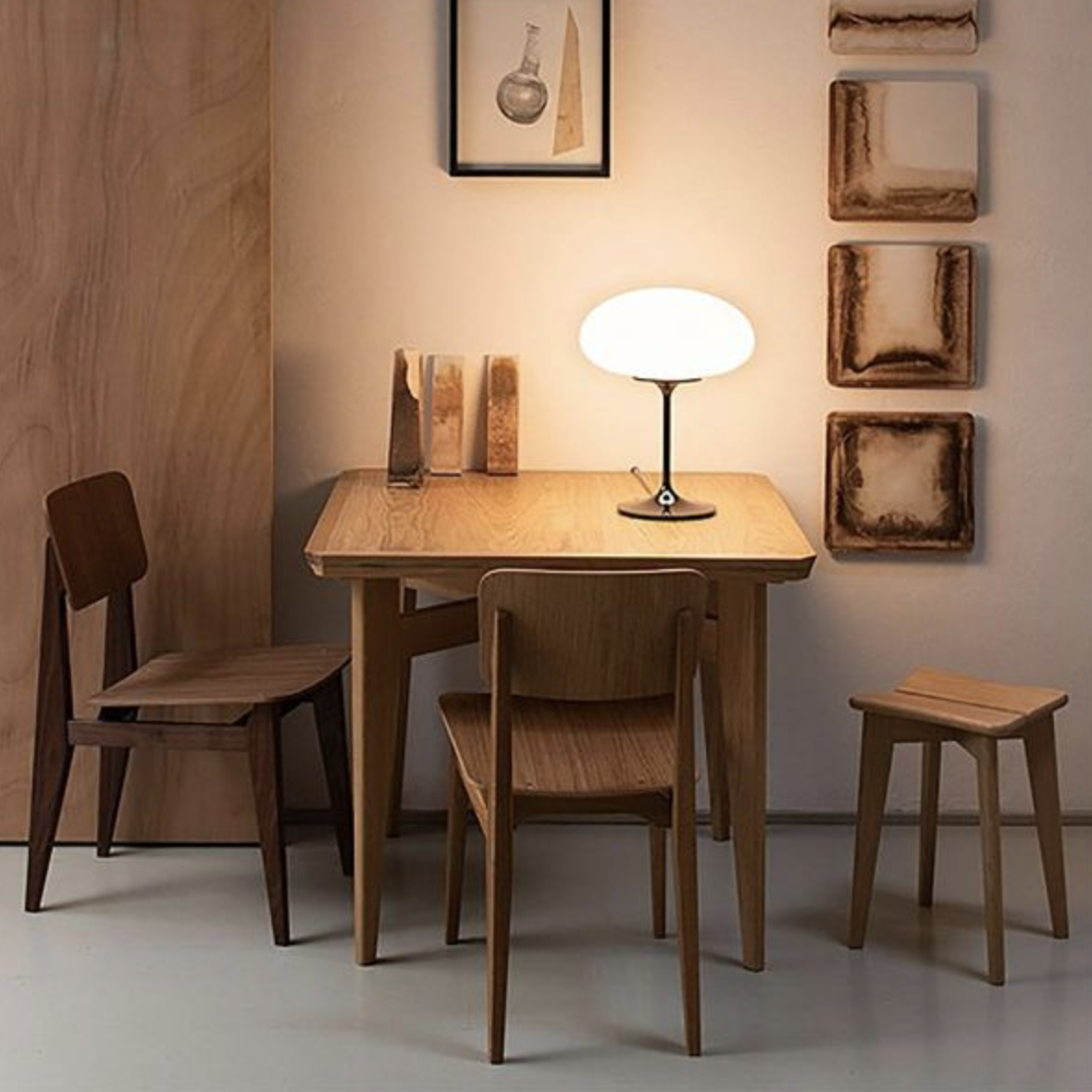 gubi table lamp on a wooden table with artwork and chairs around.