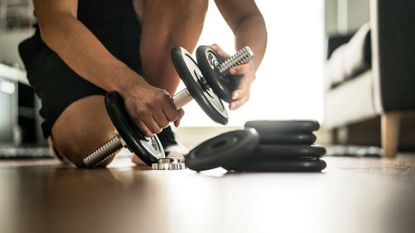 A man changing the weight of some spinlock dumbbells