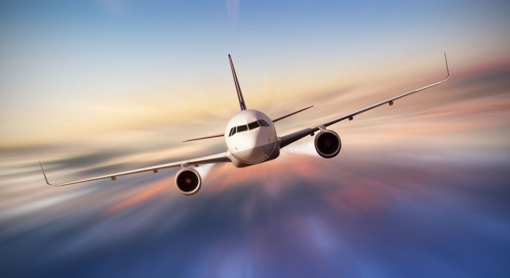 Commercial airplane flying above clouds in dramatic sunset light, blur motion. 