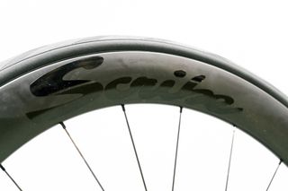 An aero road wheel stands against a white wall