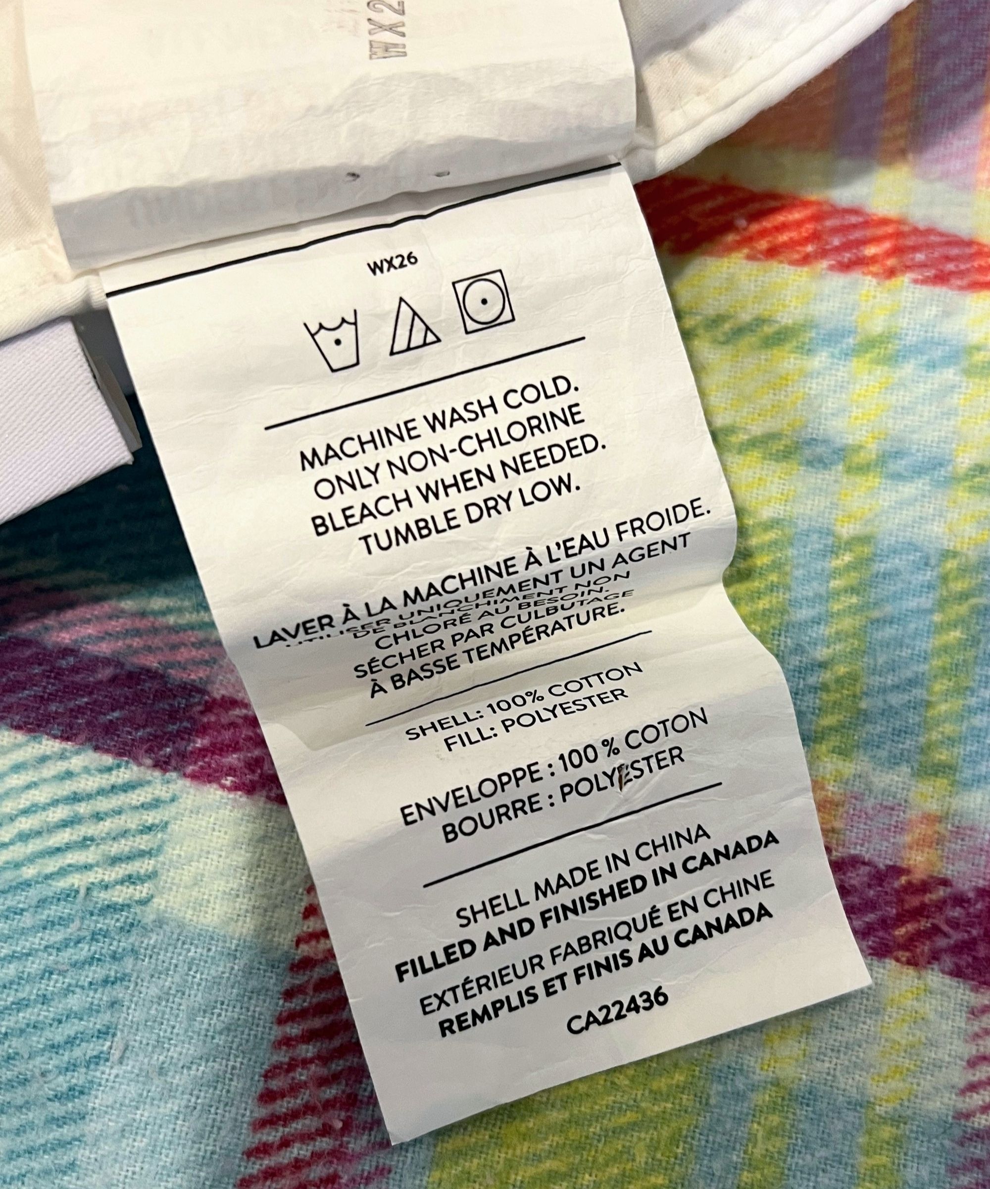 Brooklinen down alternative pillow care label photographed on colorful plaid bedding