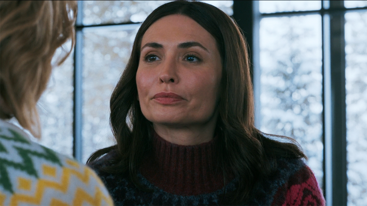 Zosia looking glum while sitting down and looking at an off-screen Carol in Pluribus episode 9