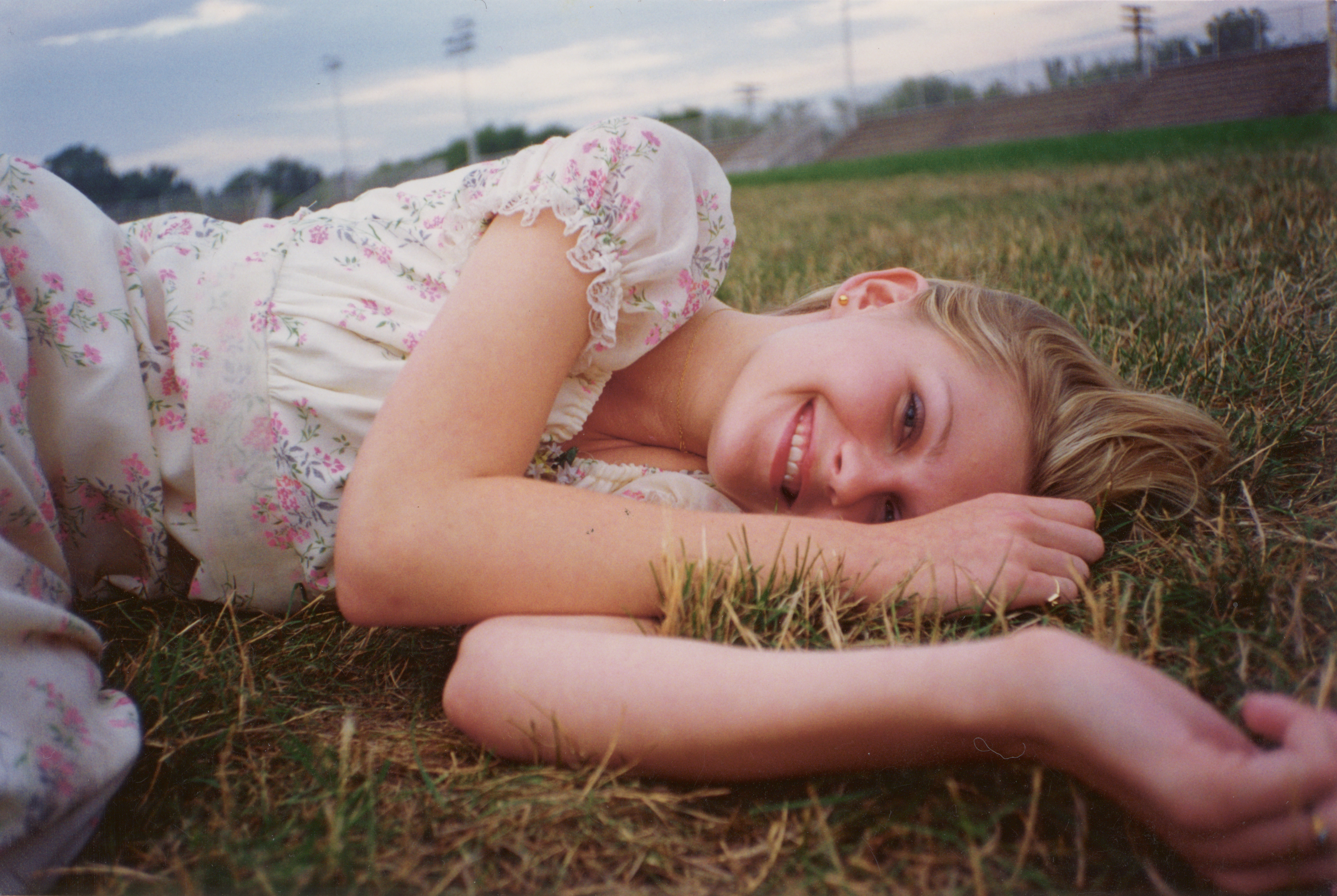 kirsten dunst as lux lisbon smiling as she wakes up on the football field in a floral dress after prom in the virgin suicides