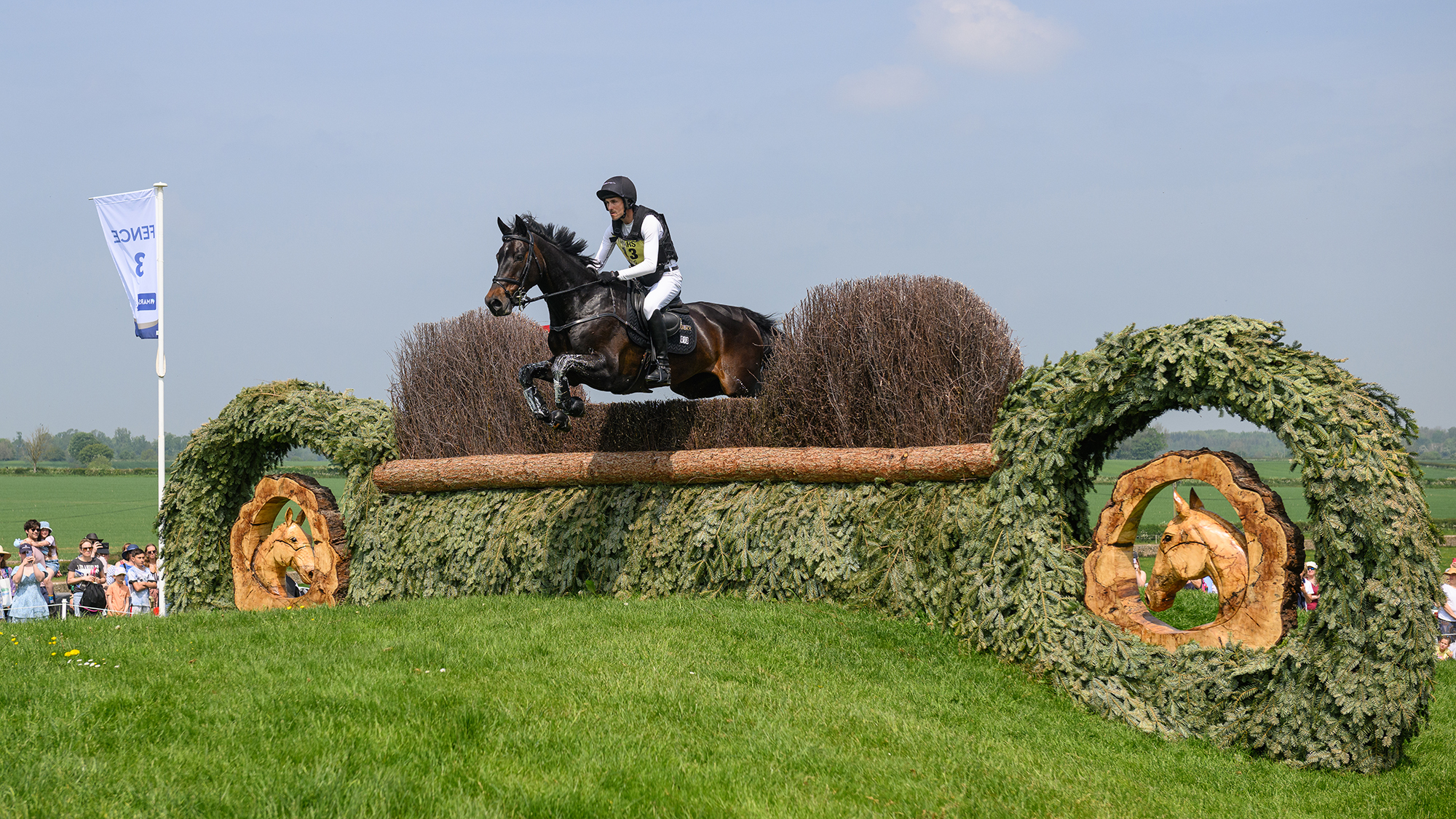 Felix Vogg and Cartania jump a brush fence at Badminton Horse Trials 2024.
