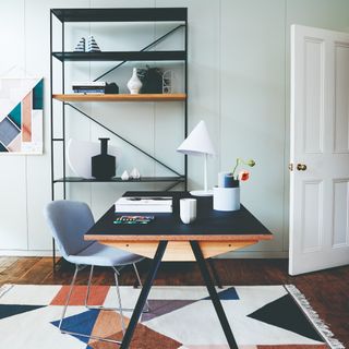 A home office with the desk placed on a colour-blocked rug facing the door