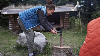 A woman chopping firewood with a hatchet
