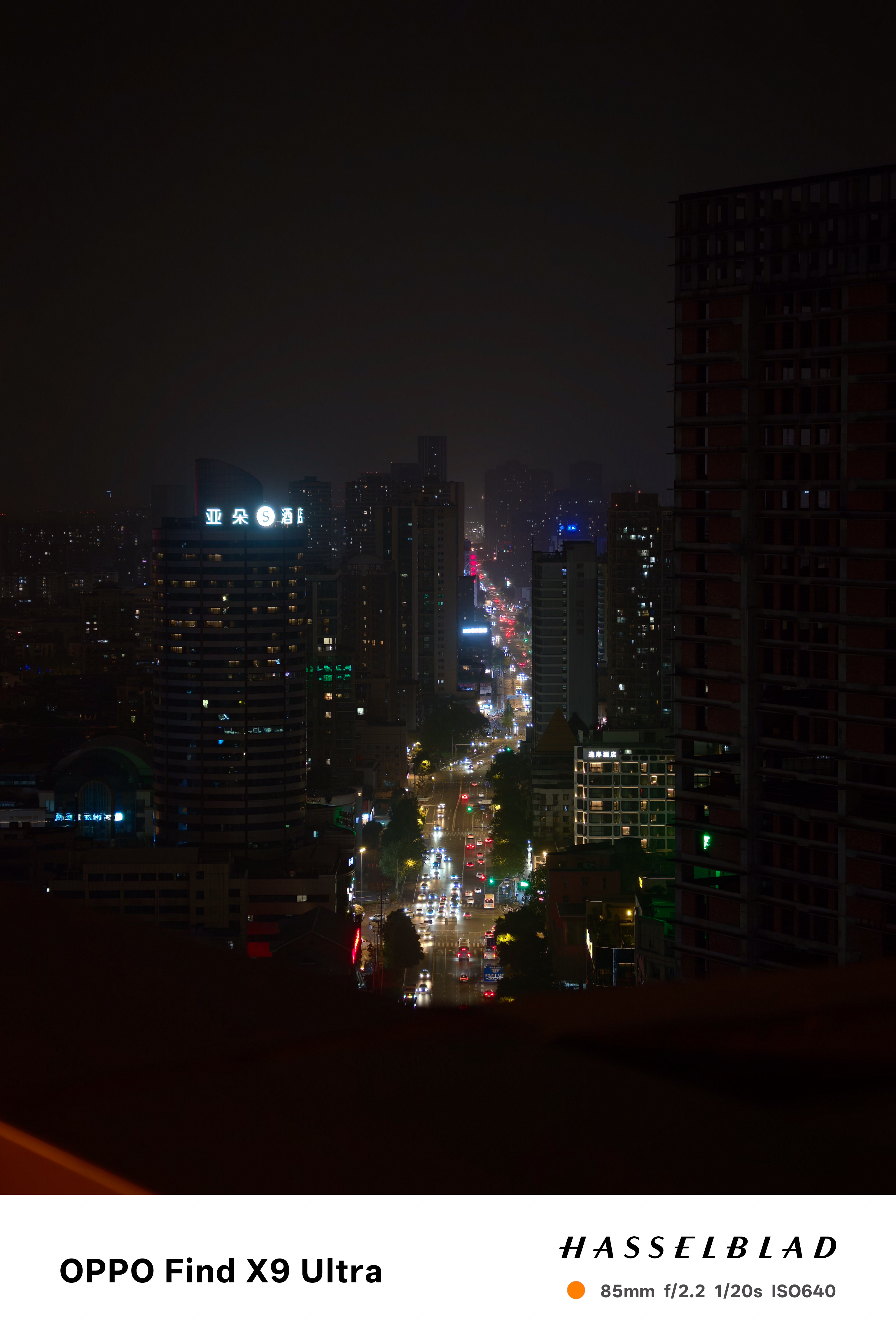Distant night cityscape with glowing traffic running between dark high-rises
