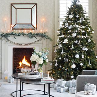 Living room with fire, decorated mantlepiece and Christmas tree with baubles and lights