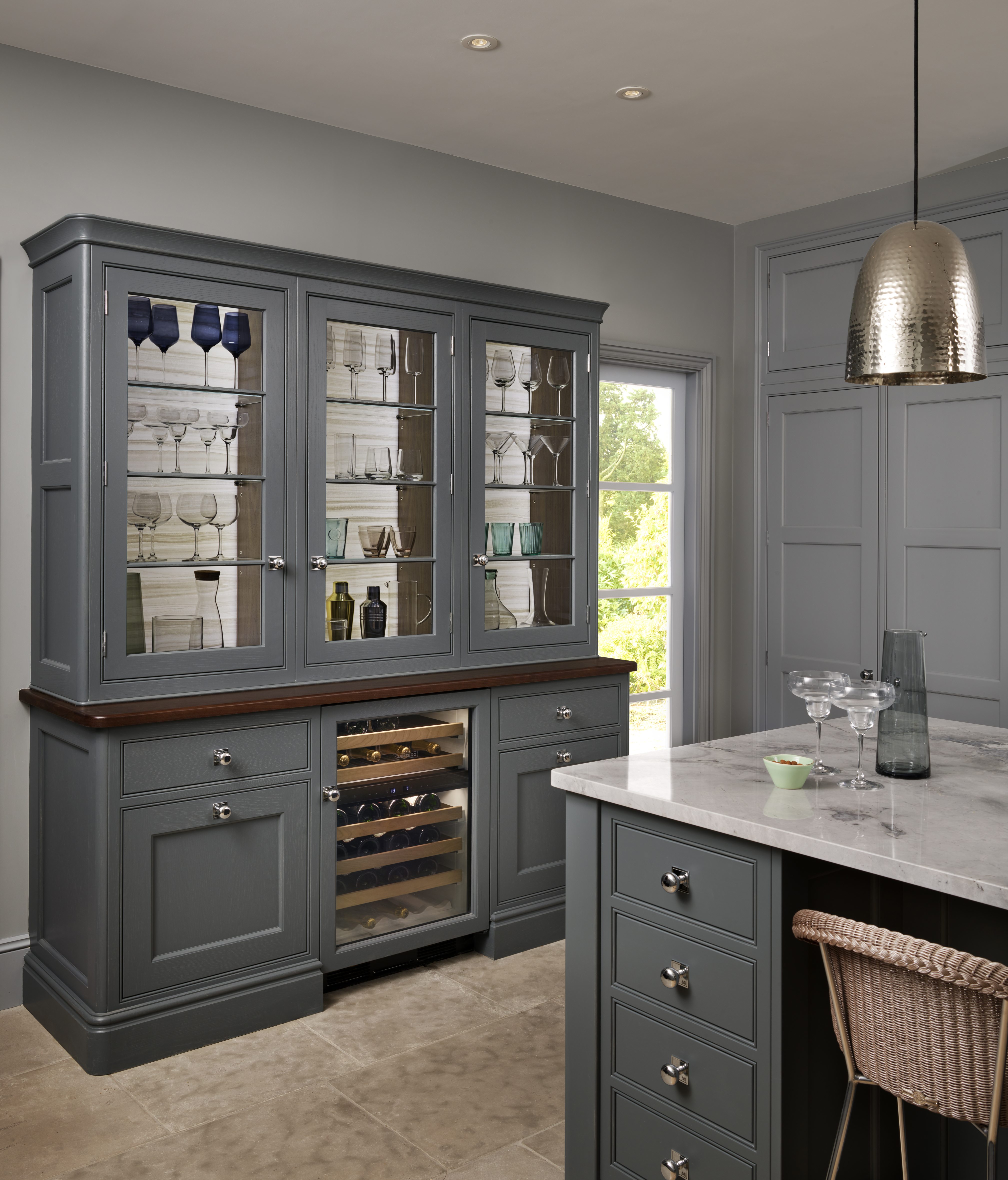 Kitchen with grey painted dresser and island, stone floor and grey walls