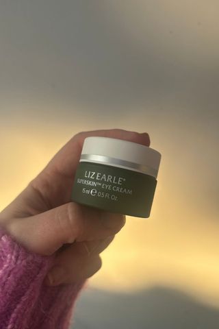 a hand holding liz earle eye cream