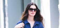 Anne Hathaway wearing a denim jumpsuit and dark sunglasses