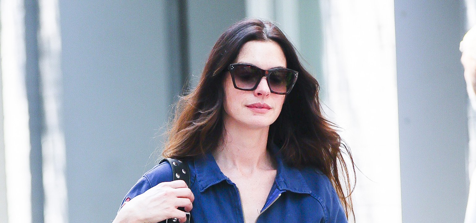 Anne Hathaway wearing a denim jumpsuit and dark sunglasses