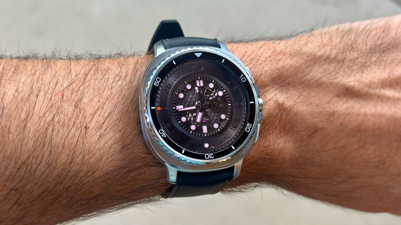 The Samsung Galaxy Watch 8 Classic on a person's wrist, showing a custom watch face from WatchMaker with a black, classic-style look.