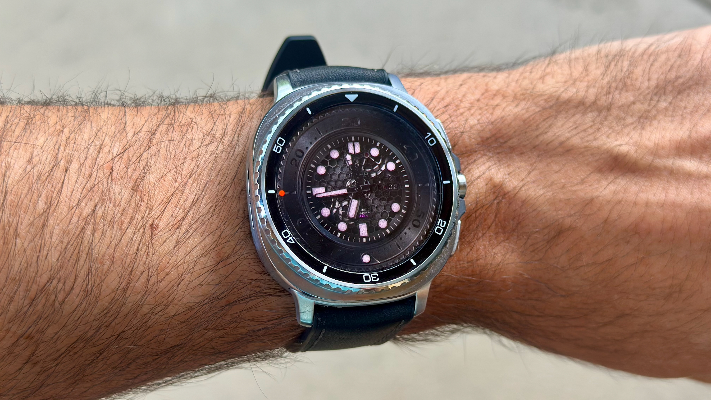 The Samsung Galaxy Watch 8 Classic on a person's wrist, showing a custom watch face from WatchMaker with a black, classic-style look.