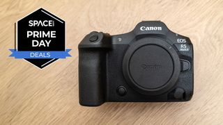 A Canon EOS R5 Mark II with the sensor cap screwed on on a wooden table with a black Space.com Prime Day deals badge in the upper left corner.
