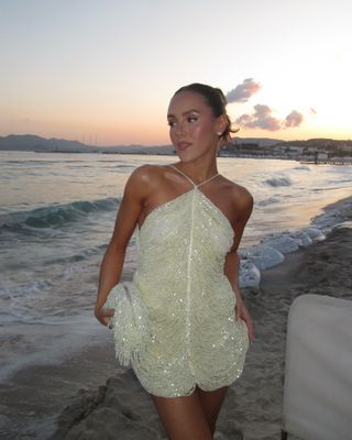 Woman wearing a sparkly minidress on the beach.