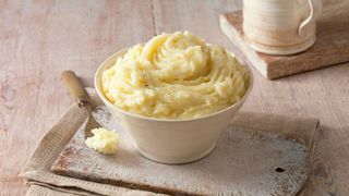 Mashed potato in bowl sitting on mat on table