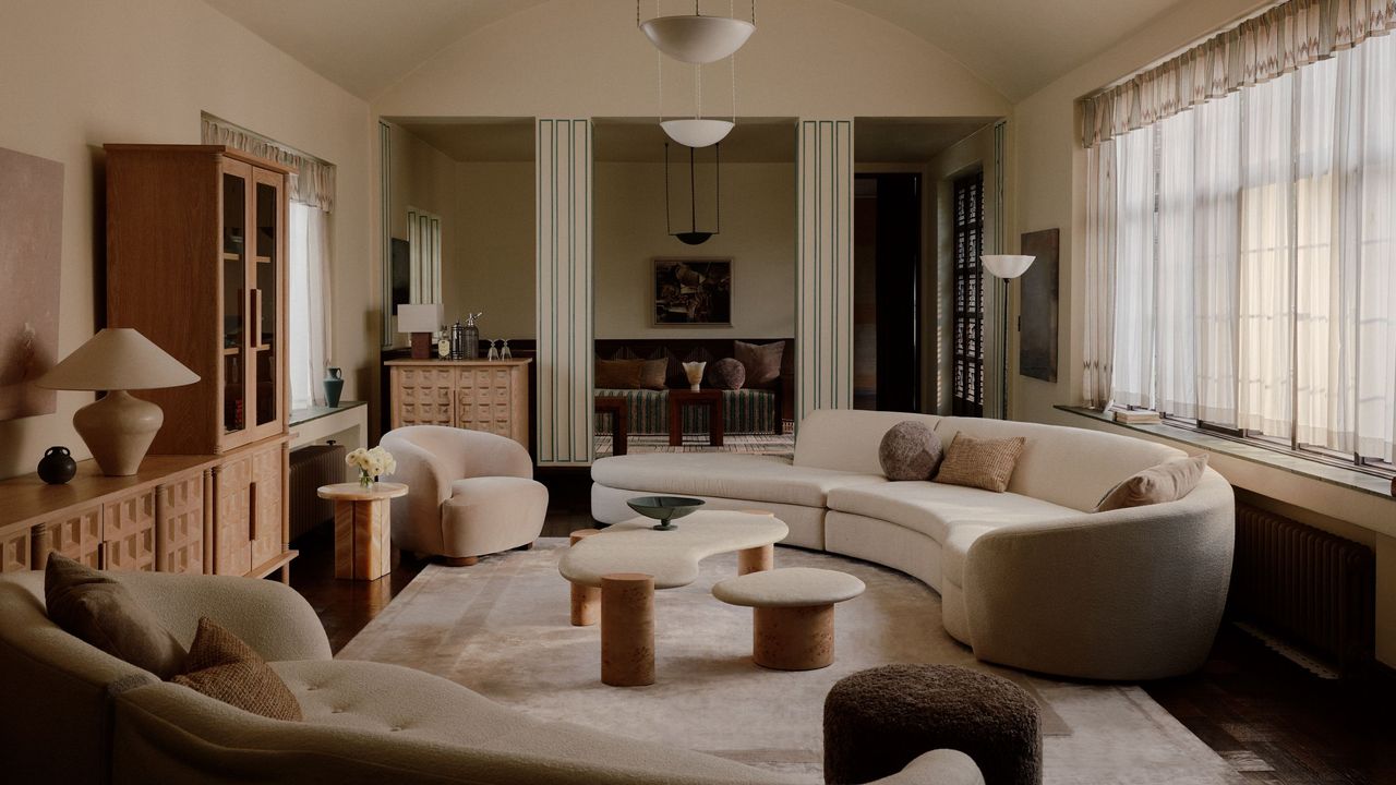 living room with curved sofa, nesting coffee table, armchairs, and vintage-inspired decor