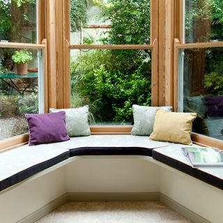 built in window bench seating in conservatory alcove, with big windows looking out on to a garden