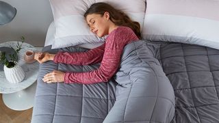 Woman sleeping under the Silentnight Wellbeing Weighted Blanket