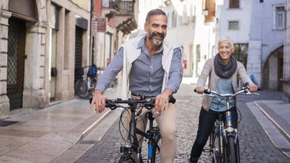 A retired American couple ride bikes through a town in Italy.