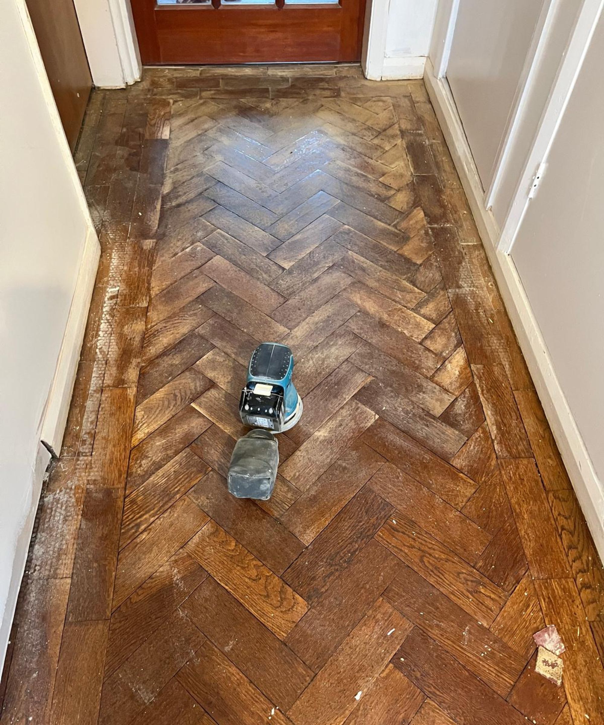 A vintage parquet floor being renovated via sanding and the application of wood dye