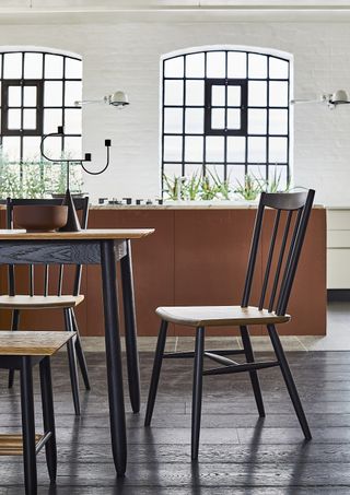 Terracotta kitchen cabinets, black Ercol dining table and chairs, and Crittall steel windows