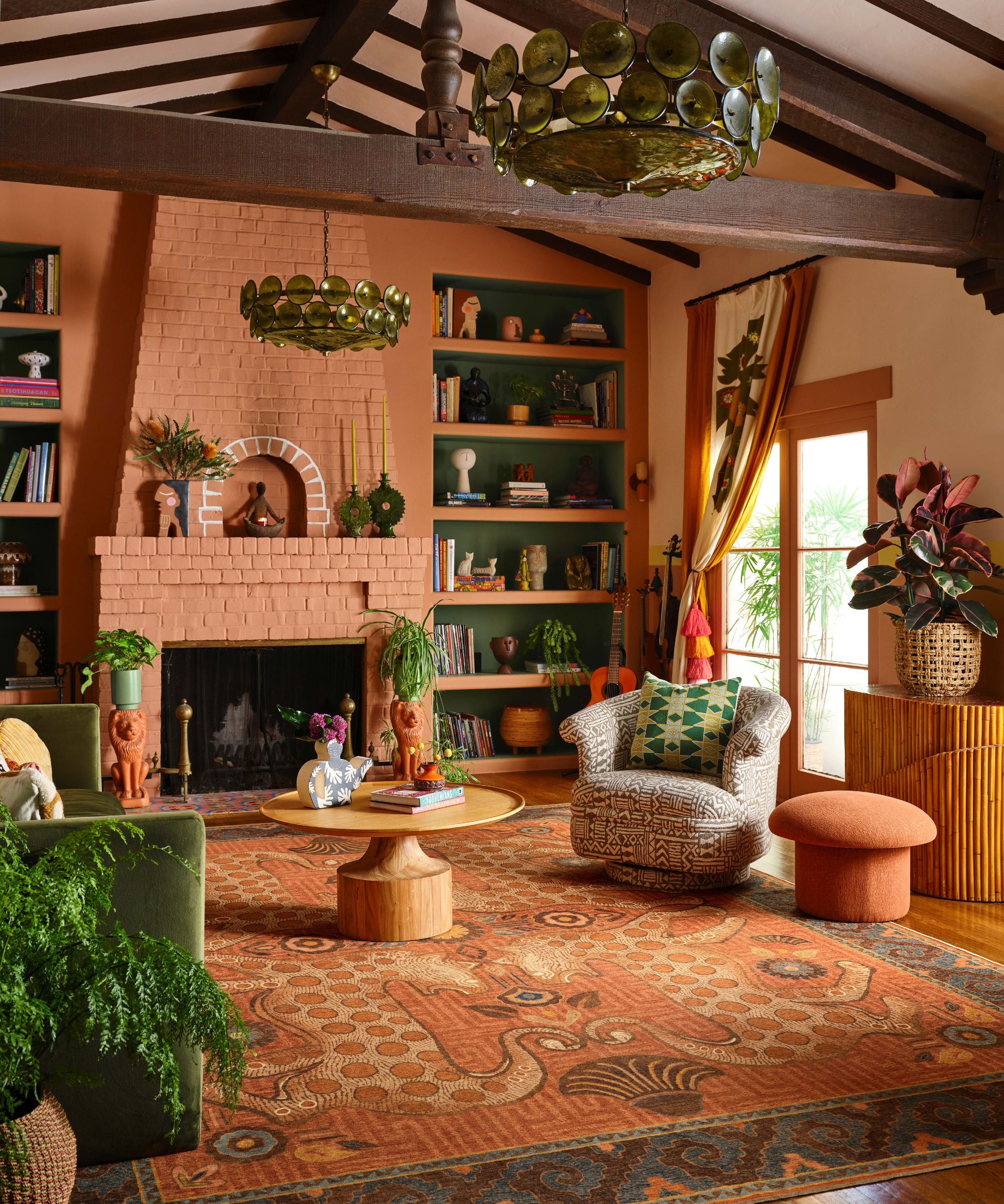 A coral living room with open shelving painted in green and decorated with books and trinkets. A large patterned area rug sits in the middle of the room