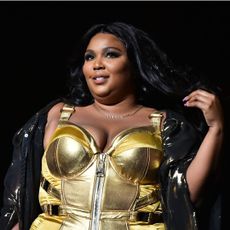 Lizzo performing on stage in a golden bodice