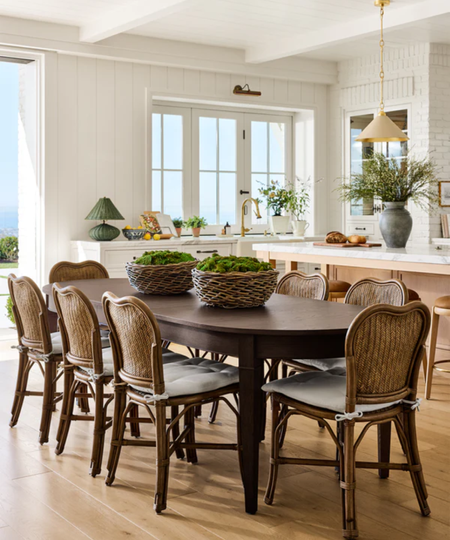a dining table with several chairs and two moss centerpieces
