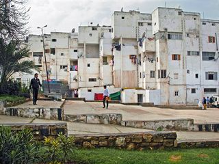 White run down building with two people walking in front of it