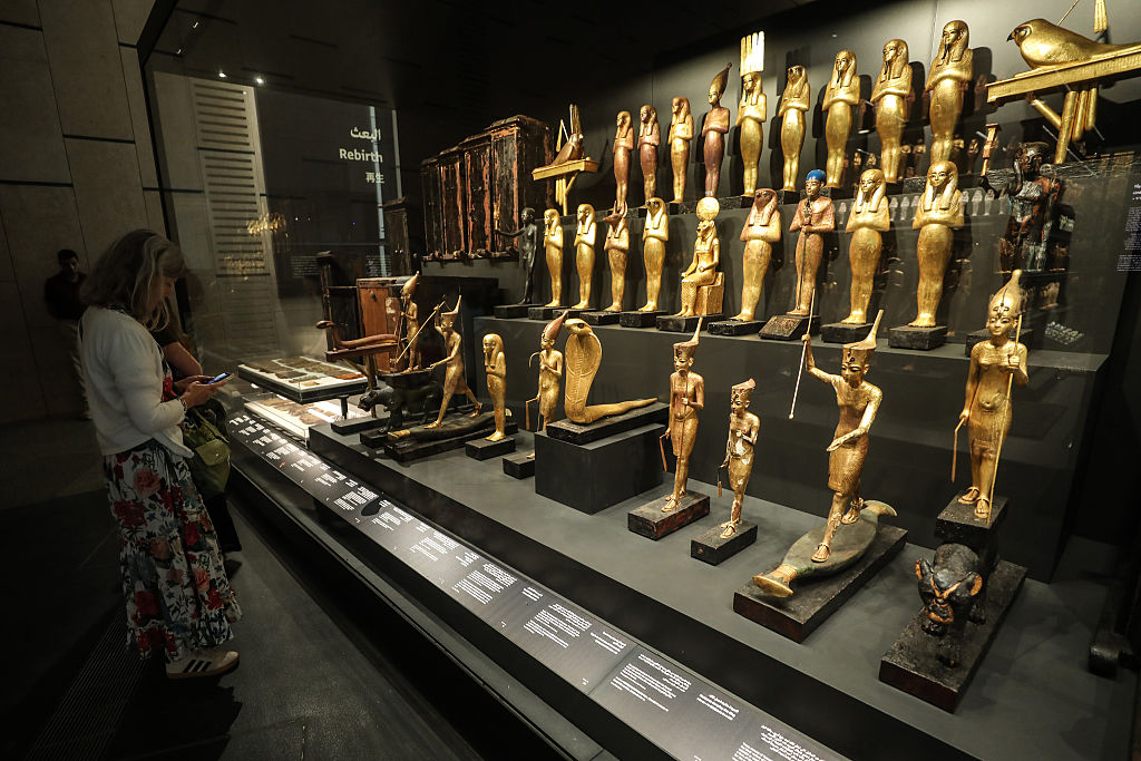 A tourist looks at a glass case full of golden artifacts housed within the new Grand Egyptian Museum.