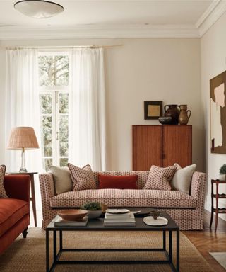 neutral living room decorated with earth tones with a rust red patterned sofa