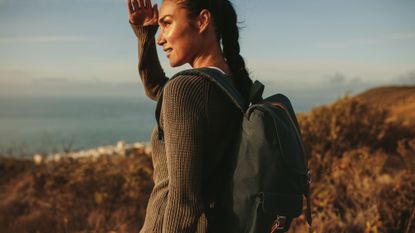 Walking workouts: A woman on a hike shielding her eyes from the sun