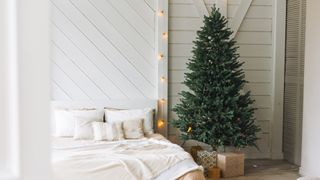 white bedroom with bare christmas tree with only fairy lights for a minimal Christmas tree decorating idea