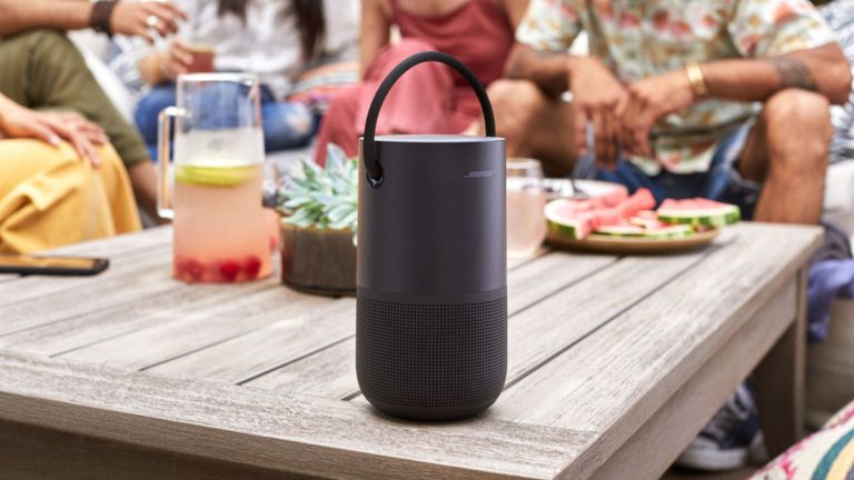 best outdoor speaker Bose Portable in black sitting on wooden garden table beside group eating and drinking